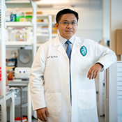 Photo of Dr. Tony Hu in a lab setting, wearing a lab coat