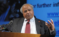 Ambassador Eric Goosby speaks at a podium at NIH, slide projected in background, picturing a young child