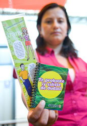 Woman holds up bookmark and pamphlet in Spanish