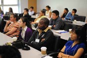 Conference attendees seated in full classroom listen attentively to speaker