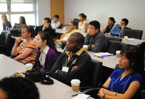 Conference attendees seated in full classroom listen attentively to speaker