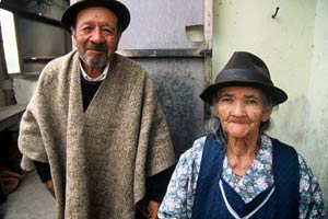 Older man and woman stand side by side facing camera, both smilin
