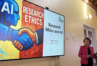 Woman wearing a pink blazer, looking at a larger screen that reads Research Ethics and AI
