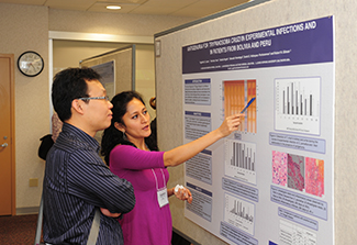 Woman points to graph on mounted conference posted, man watches