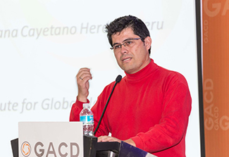 In the first photo on this page, Dr. Jaime Miranda, wearing a red shirt, stands at a podium as he lectures during a GACD meeting. 