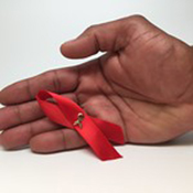 Image of a hand holding the HIV/AIDS red ribbon 