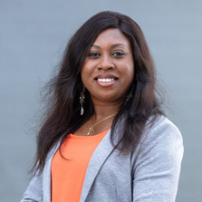 Dr. Carine Kunsevi-Kilola wears an orange shirt and blue jacket in this photo