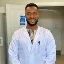 Dr. Gildas Hounmanou is pictured in this photo wearing a white doctor’s coat over a printed shirt