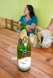 Partially empty bottle of champagne sits on table next to empty cup