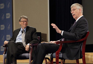 Francis Collins, speaking and gesturing with hands, seated on stage across from Bill Gates, smiling