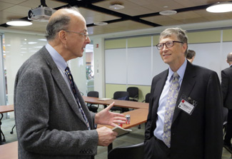 Roger Glass speaks with Bill Gates in small conference room