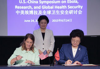 HHS Secretary Burwell and Chinese Minister Li Bin sign agreement, Chinese Vice Premier Liu Yandong watches, US and Chinese flags