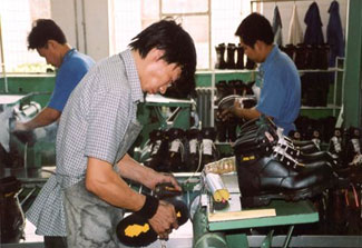 Chinese factory workers produce boots on a factory floor