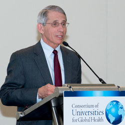 NIAID Director Tony Fauci speaks at a podium with sign reading Consortium of Universities for Global Health