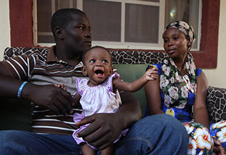 In Nigeria a father holds a happy young baby, seated next to mother