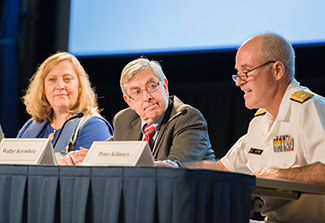 Gretchen Birbeck, Walter Koroshetz and Peter Kilmarx seated, speaking at panel table in auditorium