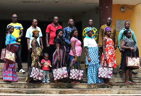 7 pregnant women line up on stairs holding shopping bags, men line up behind each of them