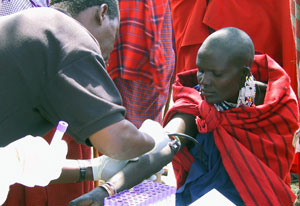 African woman extends arm to have blood drawn by a male medical worker at outdoor clinic