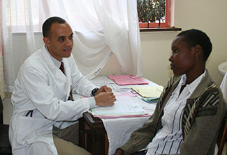 Researcher in clinic seated at a desk meets with young adult patient