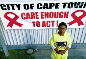 Woman wearing tshirt reading HIV positive stands in front of large sign reading city of cape town, care enough to act