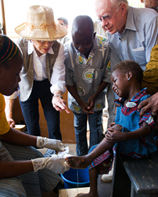 In this photo, President Jimmy Carter, wearing a blue shirt, oversees an African doctor treating a child. 