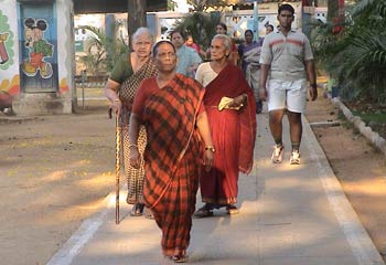 Indian people of a variety of ages walk on concrete path through outdoor park
