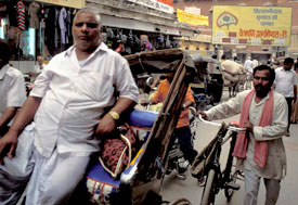 Indian men in busy street, one walks with bicycle