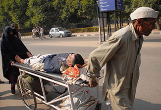 A man and woman push a stretcher holding an injured man through the streets of Chandigarh, India.