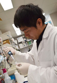 Japanese scientist Dr. Shogo Takahashi wearing white lab coat works in NIH lab with samples