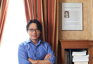 The photo on this page is a of Dr. Kaiyuan Sun, wearing a blue collared shirt and glasses. He is standing next to a plaque about Ellis McKenzie, the namesake of the library in the Stone House on the NIH Campus