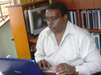 Dr. James Kiarie works on a computer seated at a desk