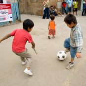 Two children playing soccer in the street