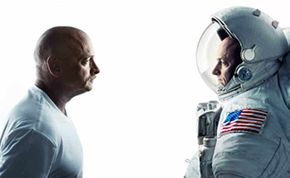 The photo shows retired astronauts Mark and Scott Kelly, identical twin brothers who participated in the NASA Twins Study, standing face to face. Mark, who remained on earth, is on the left wearing a white shirt, while Scott, who spent 340 days aboard the International Space Station, is on the right wearing an astronaut suit.