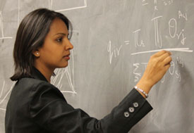 Dr Shweta Bansal intently works a complex math problem with chalk on a blackboard