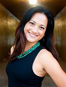 This photo shows Dr. Lisa Labita Woodson smiling and wearing a dark colored shirt and a turquoise necklace