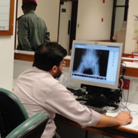 Male doctor examines x-ray on a computer monitor at desk in hospital
