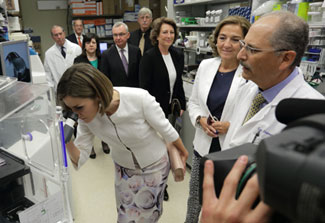 Queen Letizia of Spain peers into microscope while touring lab in NIH clinical center, NIH and Spanish leadership look on