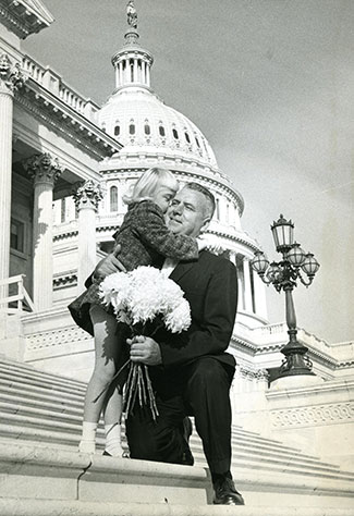 Historical photo of Rep. John E. Fogarty hugging a young girl on the outdoor steps of the US capitol building