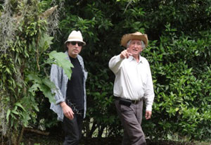 Dr Kenneth Kosik walks and talks with Colombian scientist Dr Francisco Lopera in a lush green wooded area