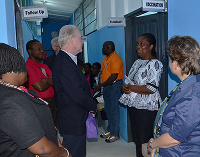Secretary Tom Price stands in a hallway listening to a woman who speaks to him in a clinic in Liberia