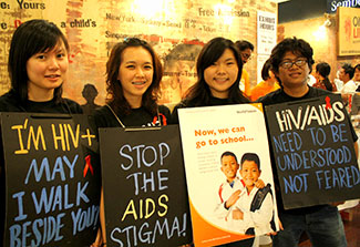 Four volunteers in Malaysia wear signboards reading: Stop the AIDS stigma!