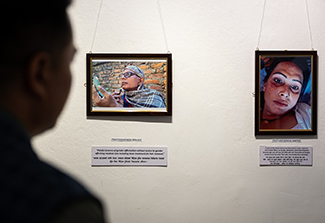 The photo on this page shows a shadowed attendee viewing two photos exhibited at the Siddhartha Art Gallery in Nepal. Both of the photos seen in this image are close-ups of Nepalese trans woman.