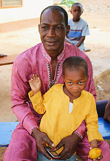 Man sits with his son outdoors in Ghana