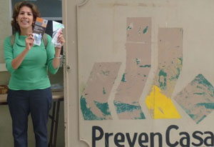 Dr. Victoria Ojeda stands holding brochures next to a sign for the PrevenCasa clinic