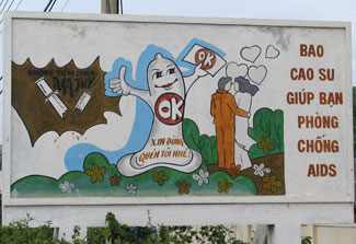 Cartoon outdoor billboard in Vietnam shows broken syringe, large condom reading “OK,” and a couple surrounded by hearts