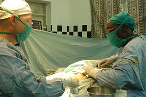 Dr. Benjamin Warf and a colleague in scrubs in operating room performing surgery