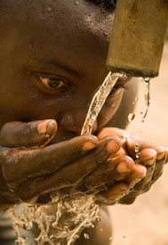 Close up of person with cupped hands drinking water flowing from a pipe