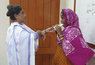 Health worker administers a test of lunch function to a woman using a spirometer.