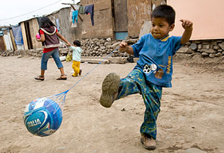A young boy plays soccer in the neighborhood street in Peru
