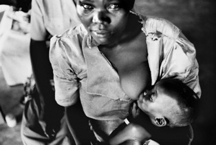 A black and white photo of an African woman nursing her baby